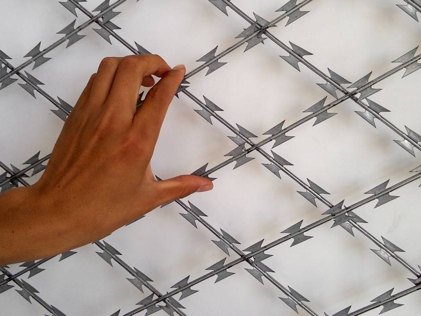 A hand is holding the stainless steel welded razor wire.